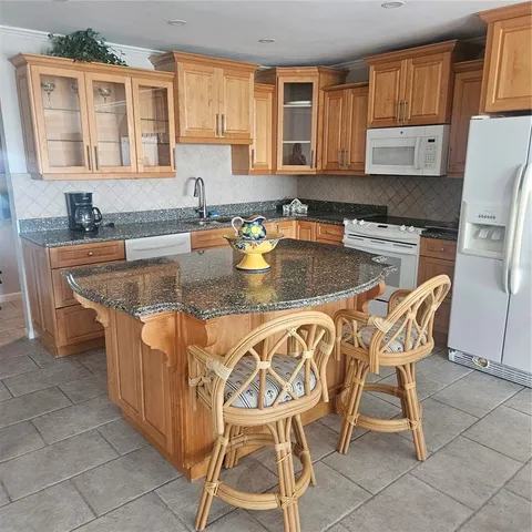 a kitchen with stainless steel appliances granite countertop a table chairs sink and cabinets