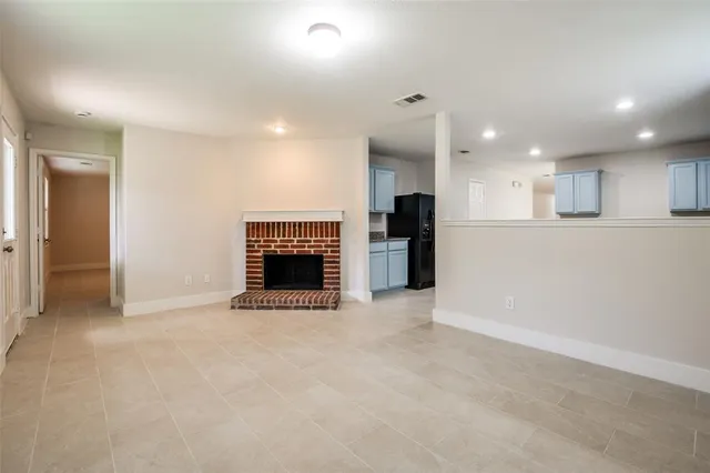 an empty room with a fireplace and a kitchen