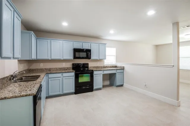 a kitchen with granite countertop a stove top oven sink and cabinets