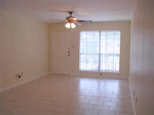 an empty room with chandelier fan and windows
