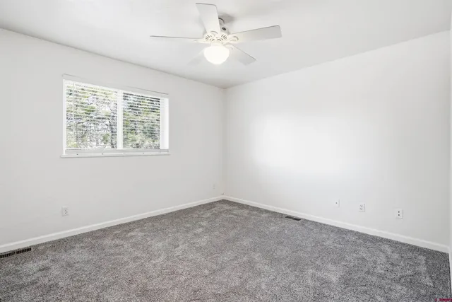 an empty room with windows and ceiling fan