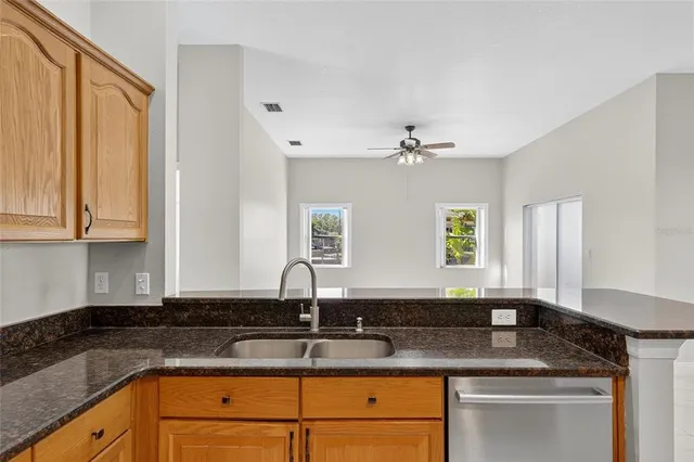 an empty room with a chandelier fan and windows