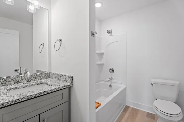 a bathroom with a granite countertop sink a toilet and bathtub