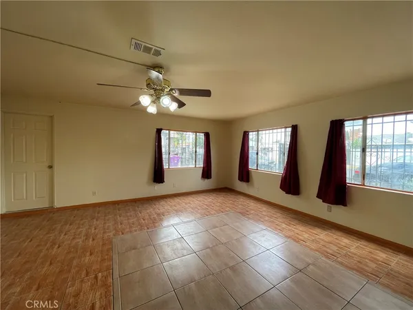 a view of an empty room with window and chandelier fan