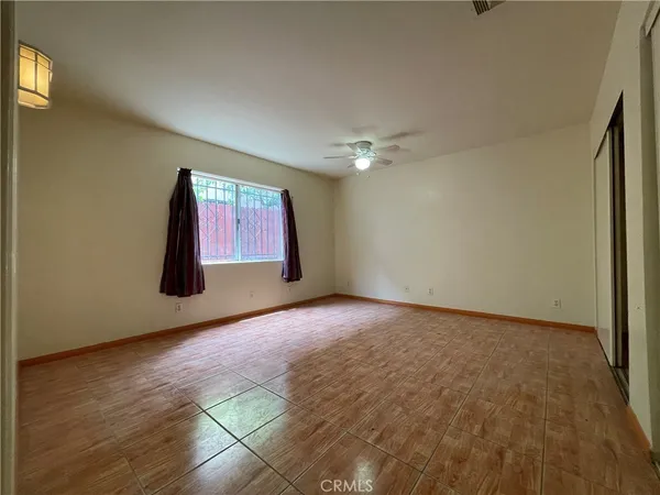 a view of an empty room with window and chandelier fan