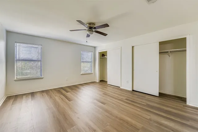 a view of empty room with wooden floor and fan