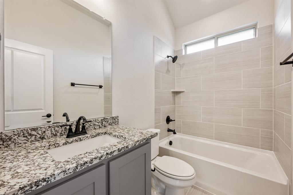 12605 Rocky Top Road Godley, TX 76044 - Photo 12 of 40 a bathroom with a granite countertop sink a toilet and bathtub