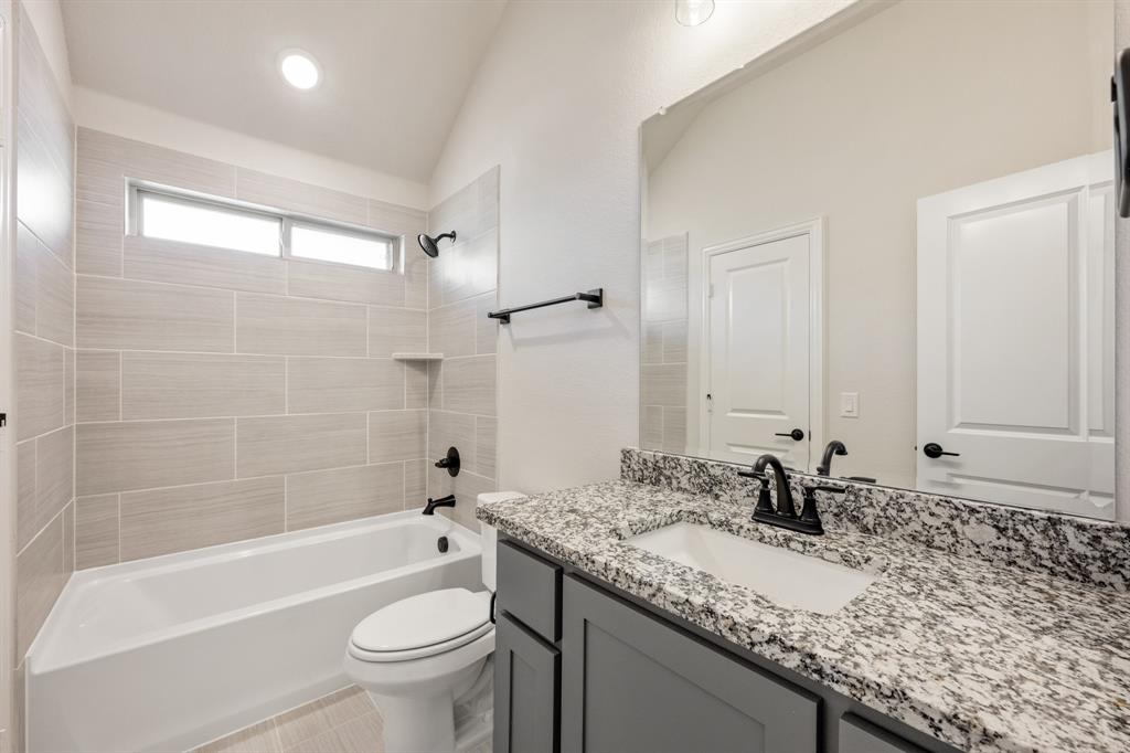 12605 Rocky Top Road Godley, TX 76044 - Photo 34 of 40 a bathroom with a granite countertop sink a toilet and bathtub