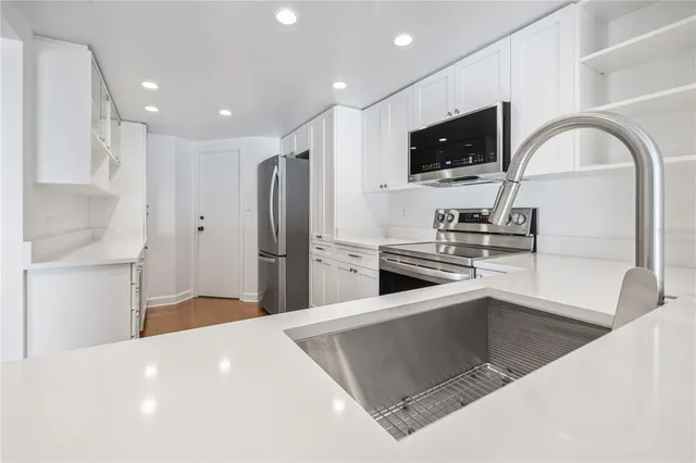 a kitchen with stainless steel appliances a stove a sink and a refrigerator