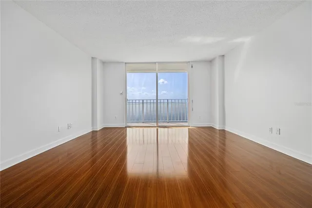 a view of an empty room with wooden floor and glass door
