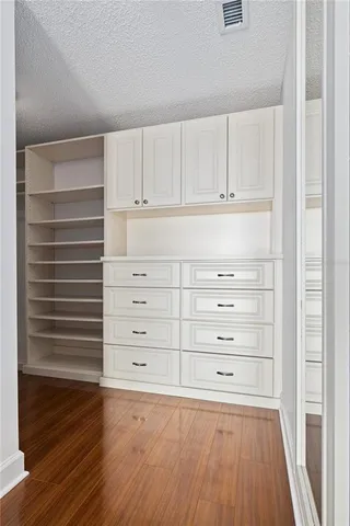 a view of an empty walk in closet with wooden floor