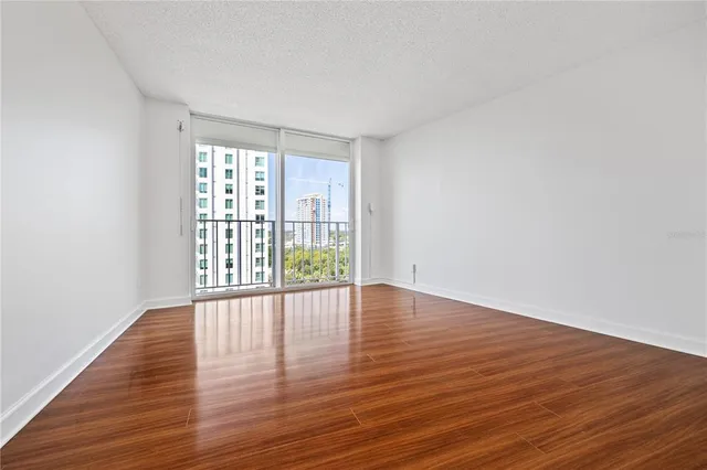 a view of an empty room with wooden floor and a window