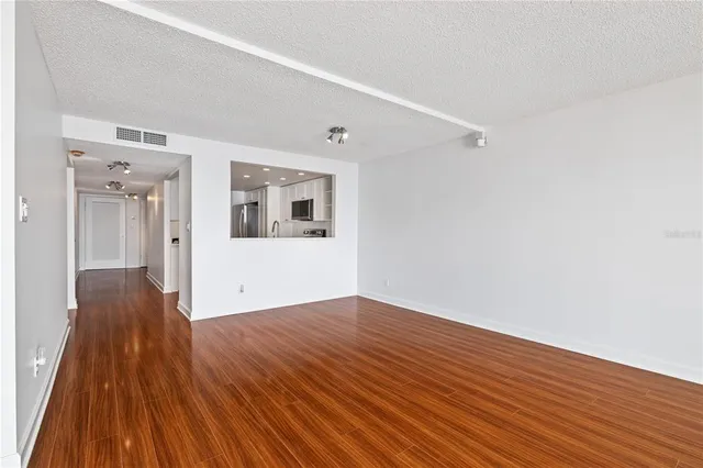a view of a big room with wooden floor and windows