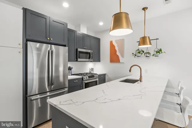 a kitchen with stainless steel appliances a refrigerator sink and wooden floor