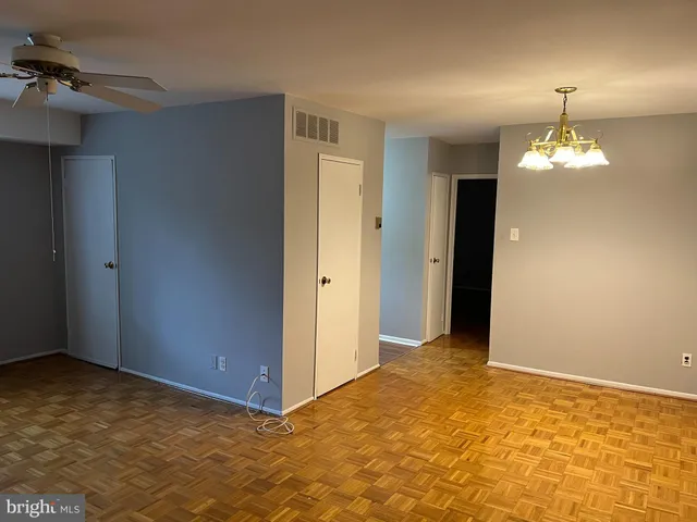 a view of an empty room and a chandelier fan