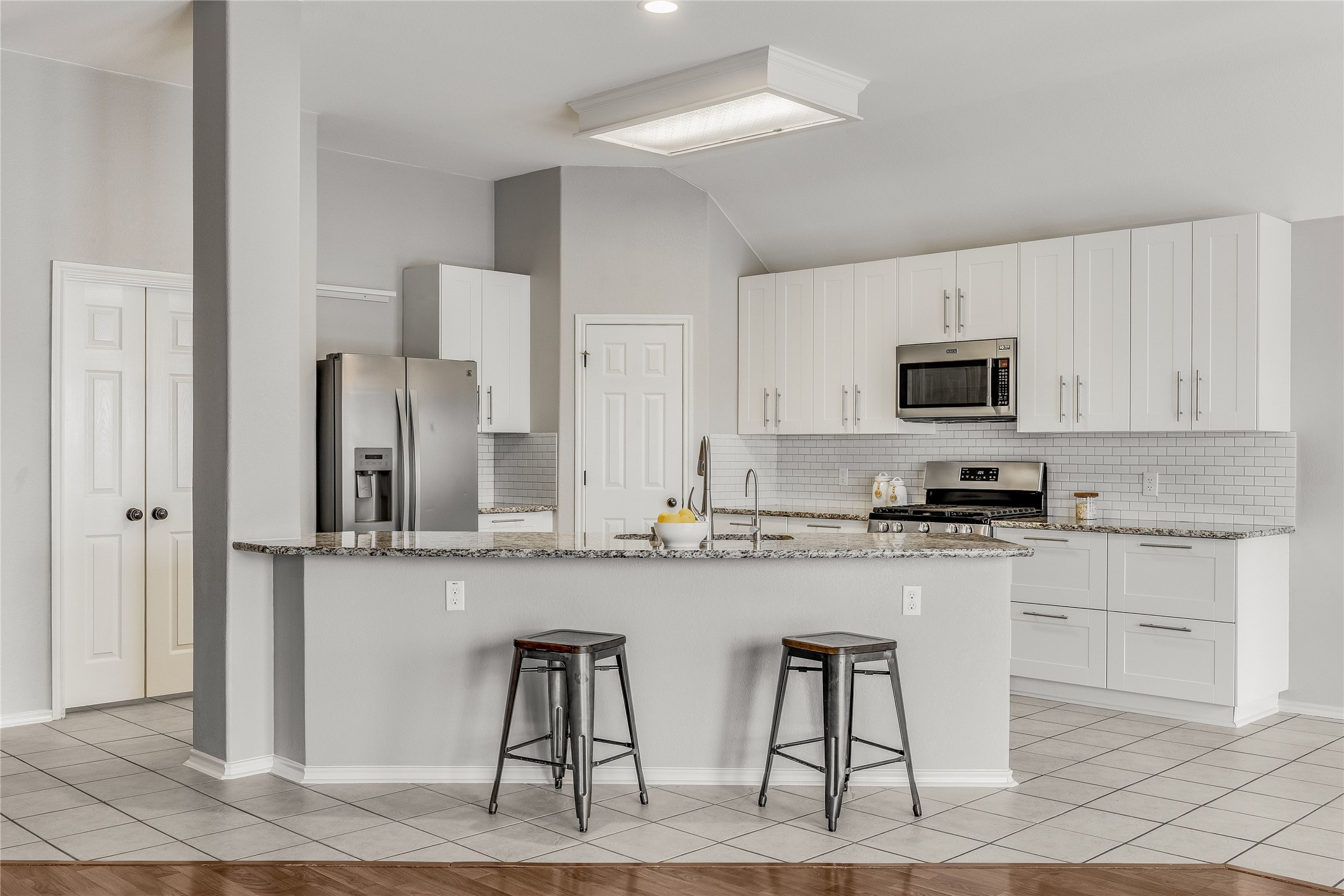 a kitchen with stainless steel appliances granite countertop a stove top oven a sink a refrigerator and white cabinets