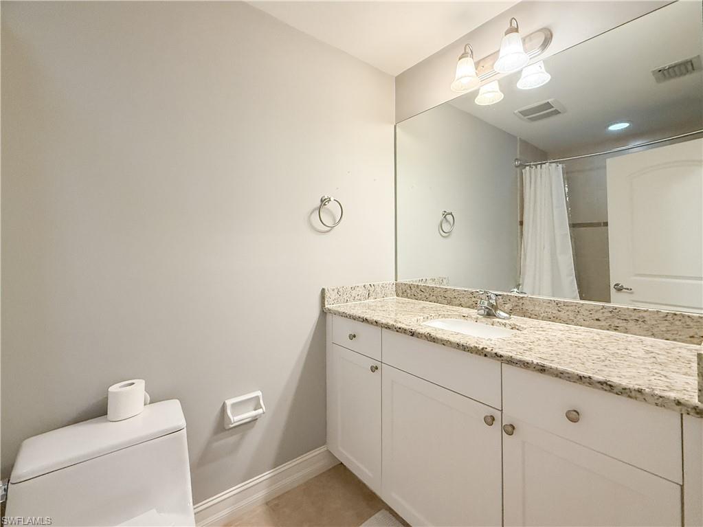 1100 Pine Ridge Road, Unit B405 Naples, FL 34108 - Photo 32 of 43 a bathroom with a granite countertop sink a toilet and a mirror