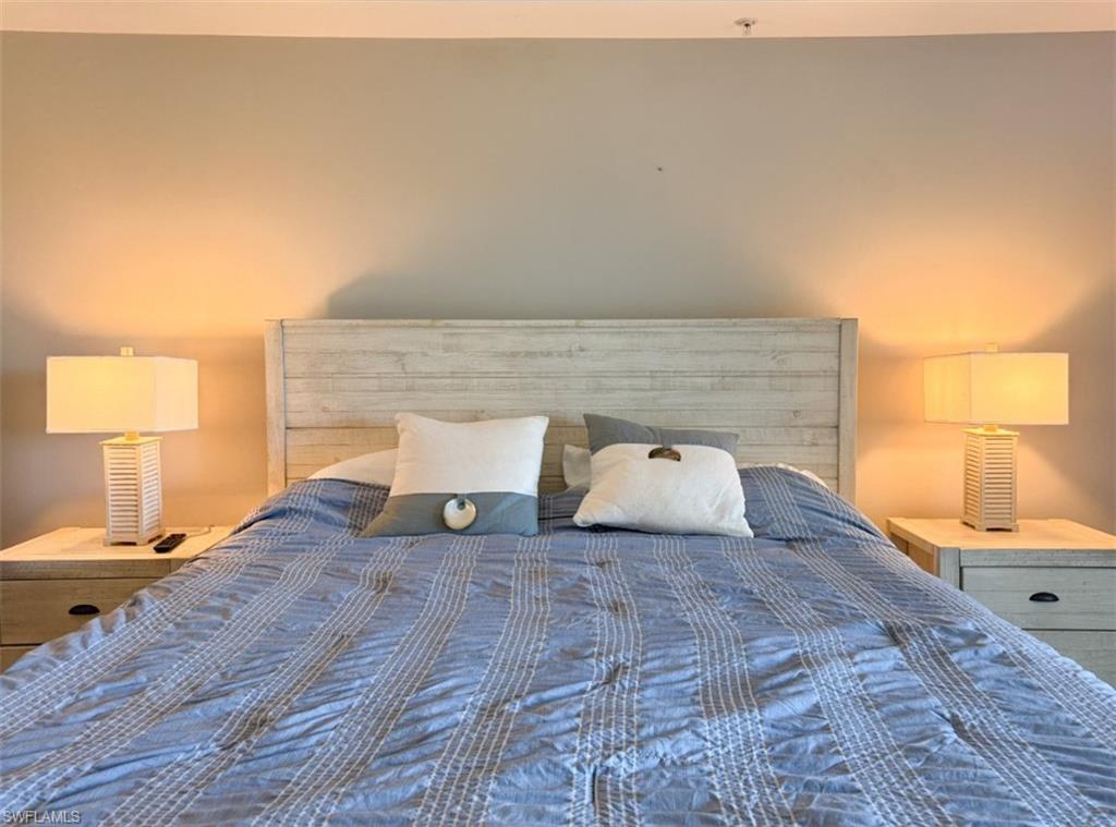 1100 Pine Ridge Road, Unit B405 Naples, FL 34108 - Photo 34 of 43 a view of a bedroom with a bed and lamp on dresser