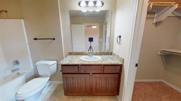 a bathroom with a granite countertop sink a toilet and a mirror