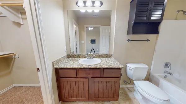 a bathroom with a granite countertop toilet a sink and a mirror