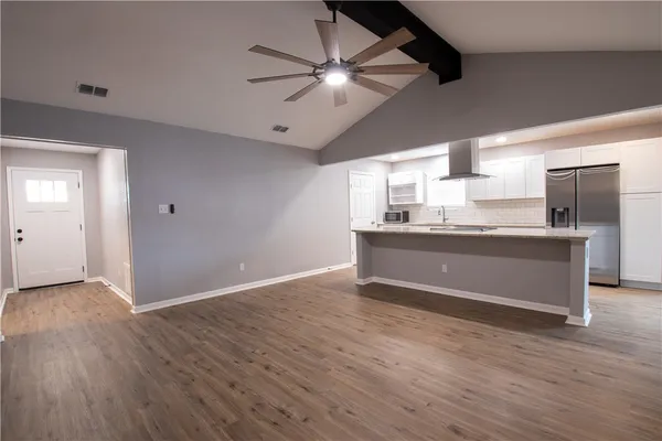 a room with kitchen island stainless steel appliances sink cabinets and wooden floor