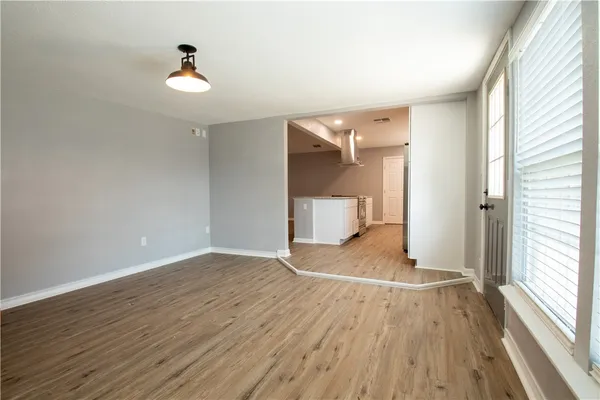 a view of empty room with wooden floor and fan