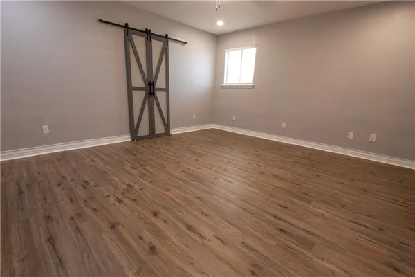 a view of empty room with wooden floor and window