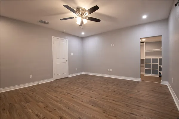 an empty room with wooden floor and a ceiling fan