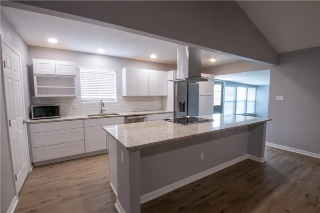 a large kitchen with a sink and dishwasher a stove top oven with wooden floor