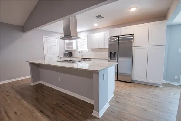 a kitchen with kitchen island granite countertop a sink cabinets and stainless steel appliances