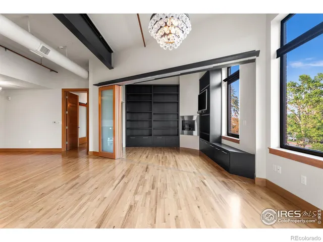 a view of empty room with wooden floor and window