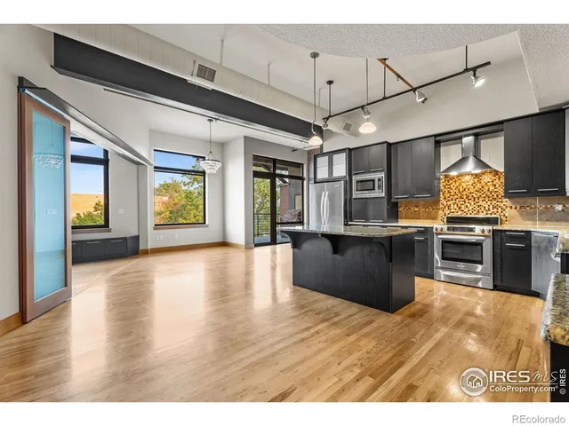 a large kitchen with stainless steel appliances granite countertop a large counter top and wooden floors