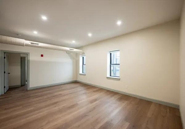 an empty room with wooden floor and windows