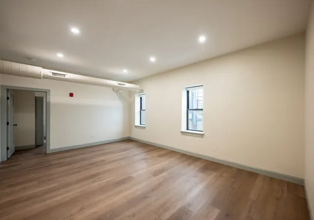 an empty room with wooden floor and windows