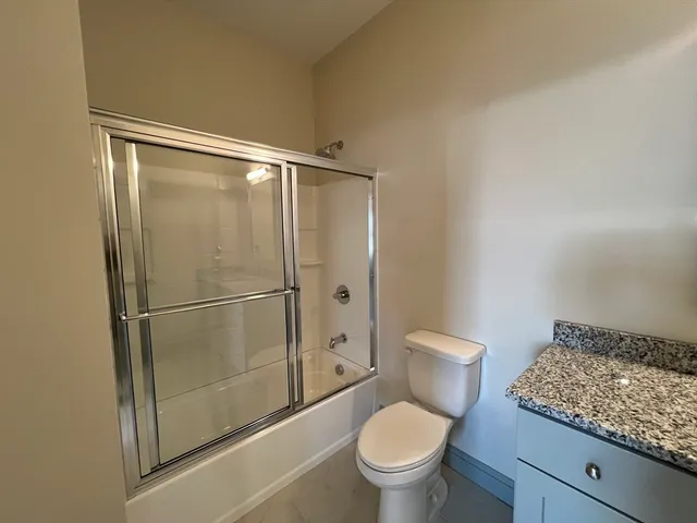 a bathroom with a granite countertop toilet and a sink