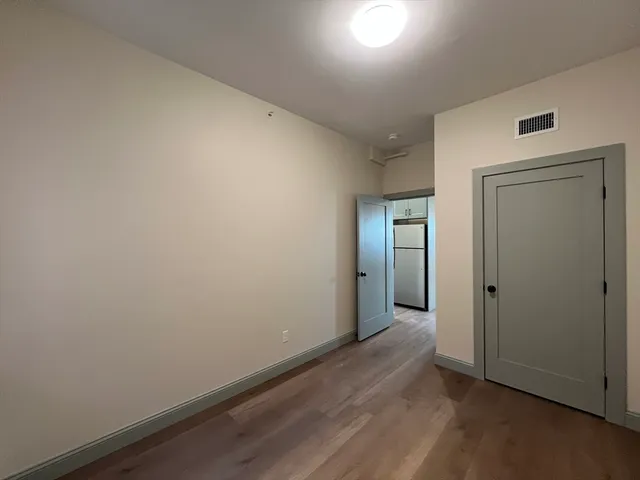 an empty room with wooden floor and mirror