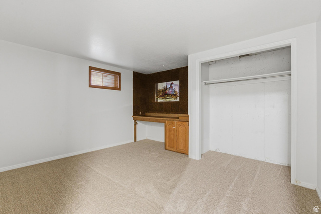 148 Tennyson Avenue Sandy, UT 84070 - Photo 35 of 55 Carpeted room featuring a built-in desk with wooden cabinetry, a wood-framed window with blinds, and an open closet
