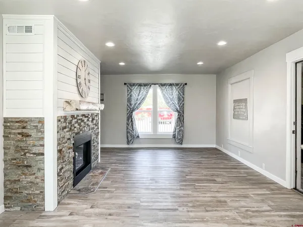 an empty room with wooden floor fireplace and windows