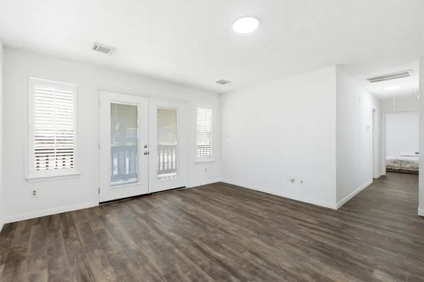an empty room with wooden floor and windows
