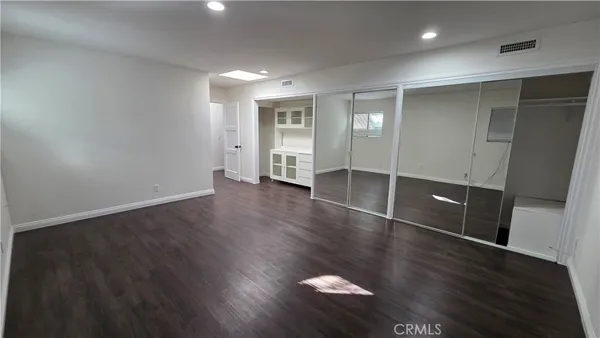 an empty room with wooden floor and a mirror
