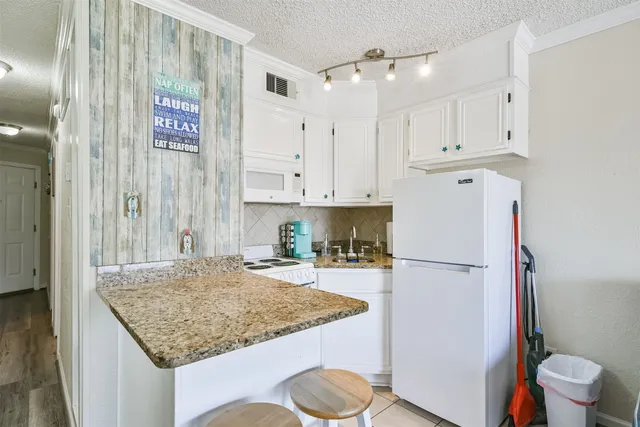 a kitchen with stainless steel appliances granite countertop a refrigerator sink and white cabinets