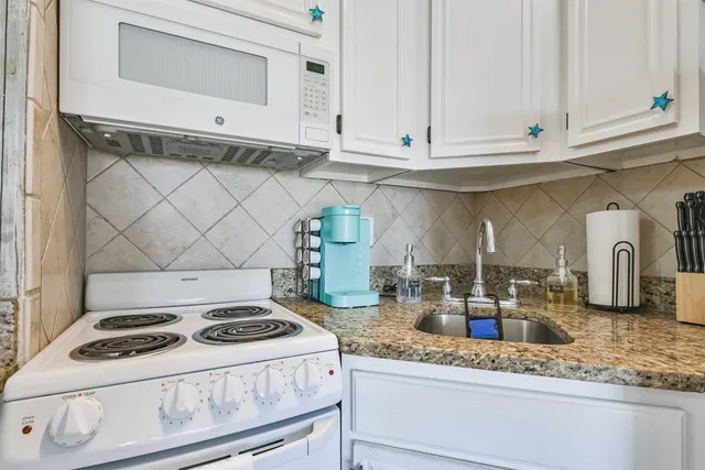 a kitchen with granite countertop white cabinets and a stove