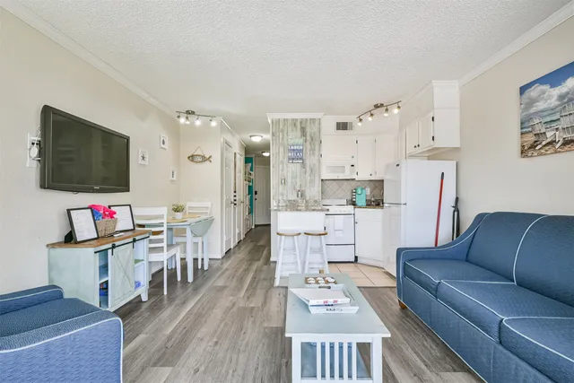 a living room with furniture a flat screen tv and kitchen view
