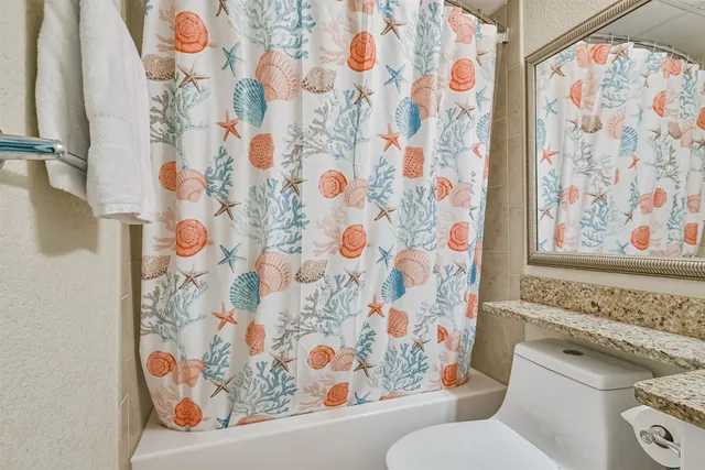 a bathroom with a toilet and a shower curtain
