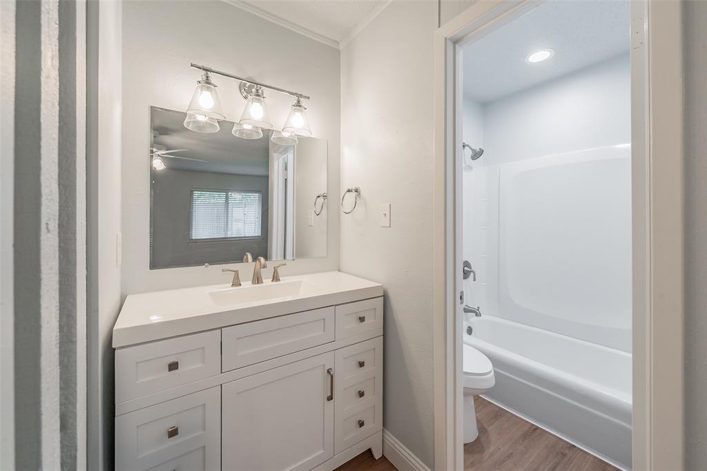 1301 Cedar Ridge Terrace Euless, TX 76039 - Photo 20 of 31 Primary en-suite bathroom with updated vanity, light fixtures, and tub surround. Luxury vinyl floor for easy care.