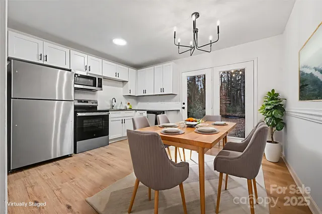 a kitchen with stainless steel appliances granite countertop a dining table chairs refrigerator and cabinets