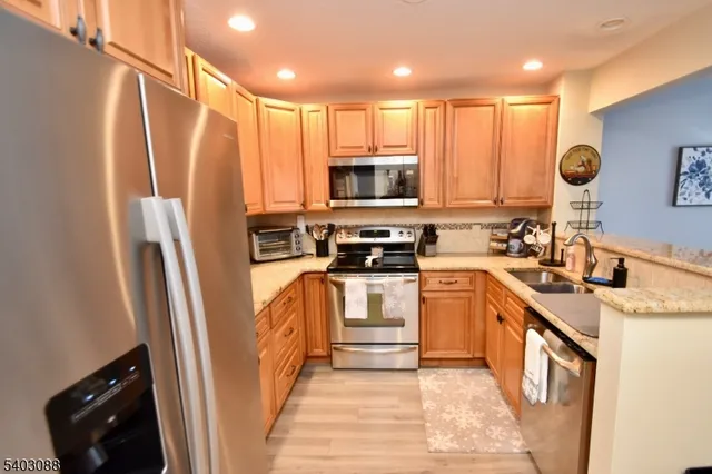 a kitchen with stainless steel appliances granite countertop a refrigerator a stove a sink and a microwave