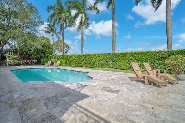 a view of swimming pool of water with lawn chairs and palm tree