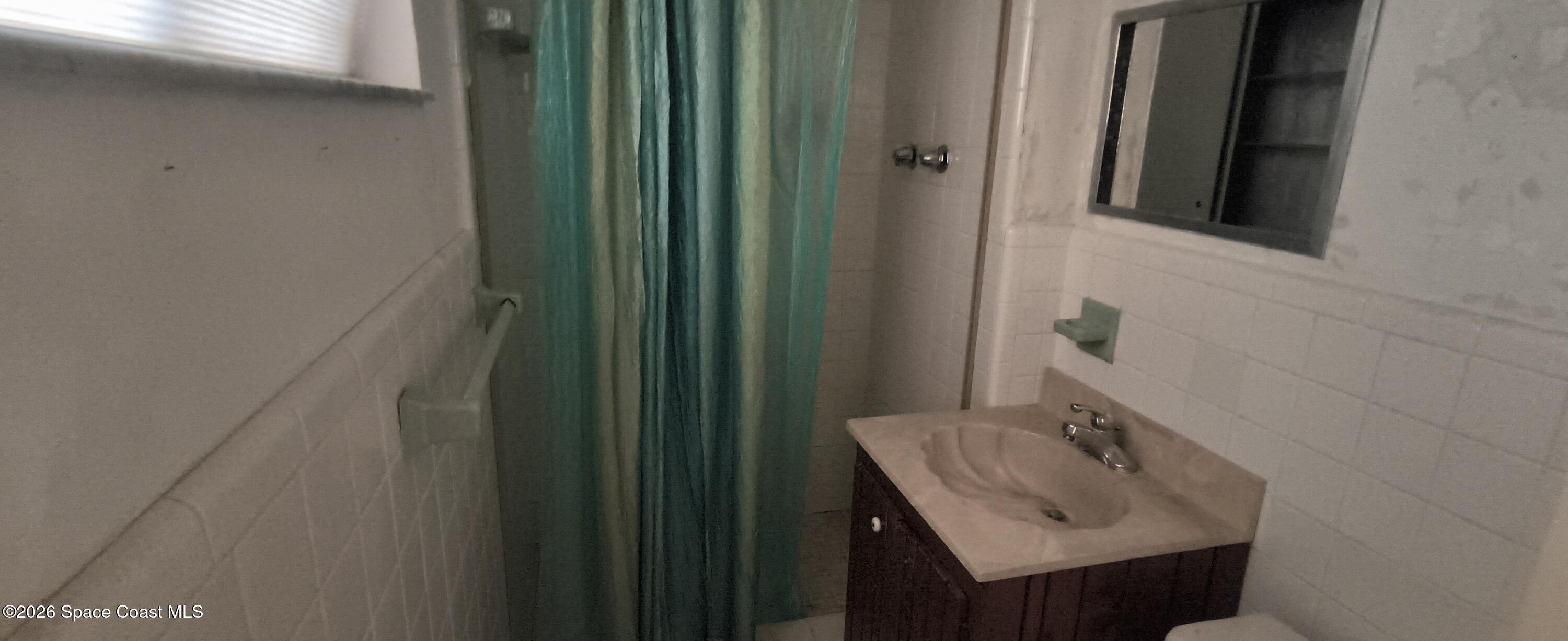 801 Espanola Way Melbourne, FL 32901 - Photo 12 of 18 a bathroom with a sink a mirror and shower