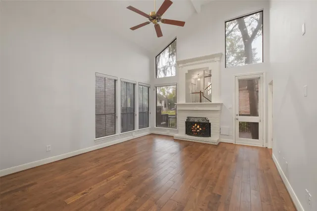 a view of an empty room with wooden floor fireplace and a window